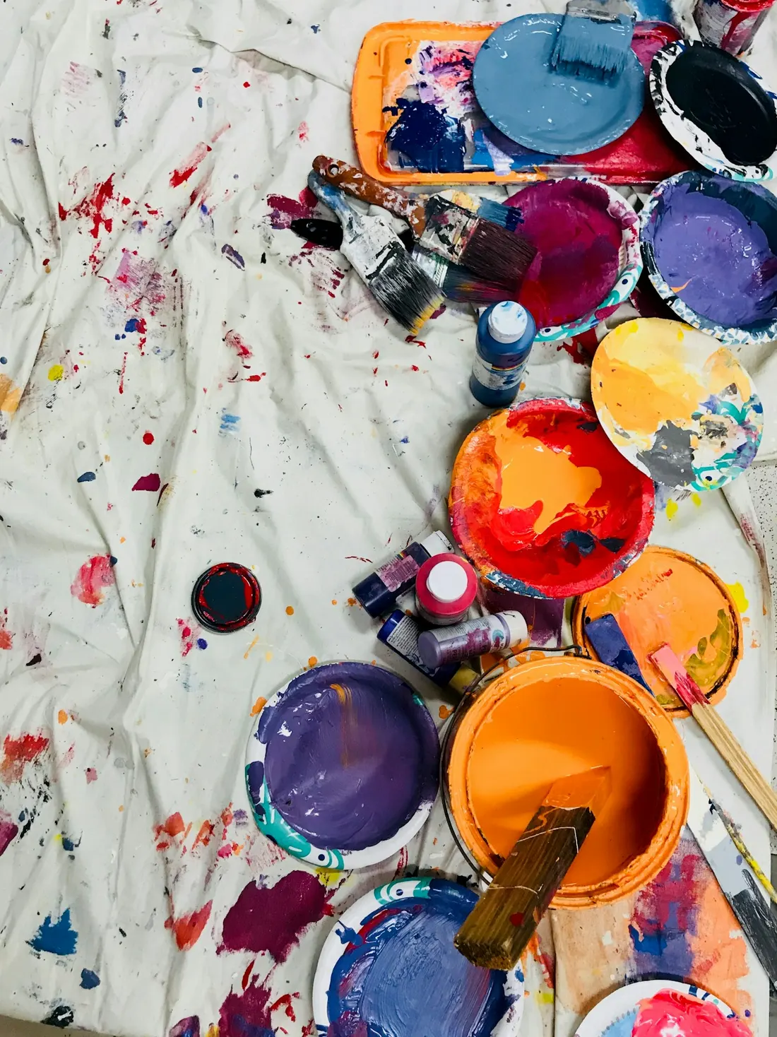 Paint cans, rollers, and drop cloths staged for a residential painting project