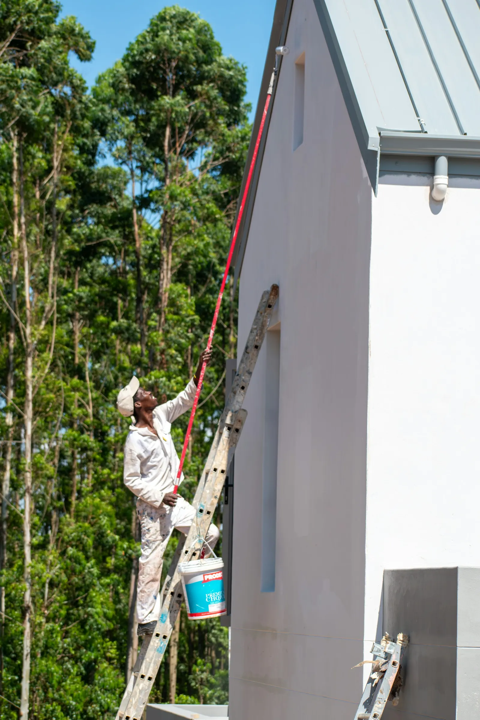 Painter working on a building exterior from a ladder