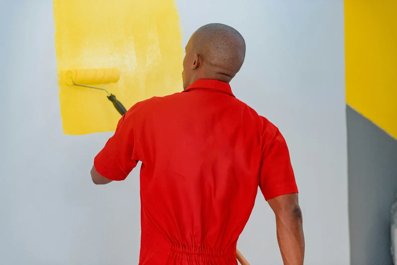 Painter applying yellow paint to an interior wall