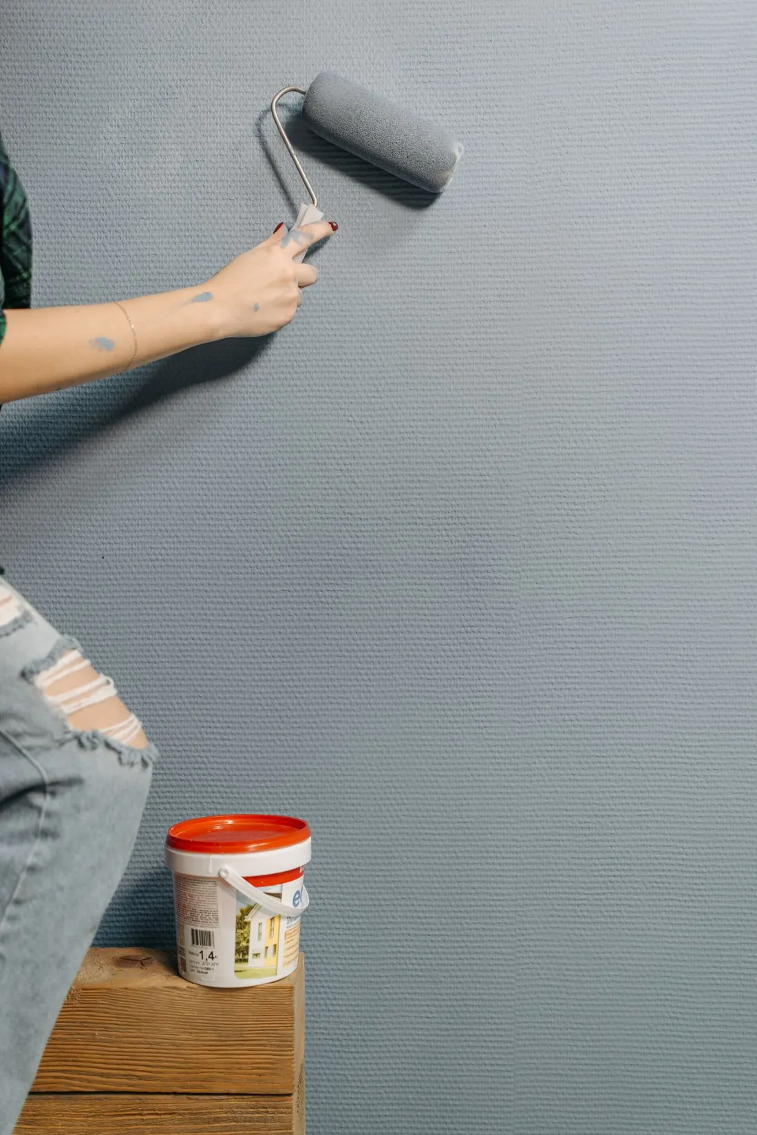 Painter applying blue-gray paint to an interior wall
